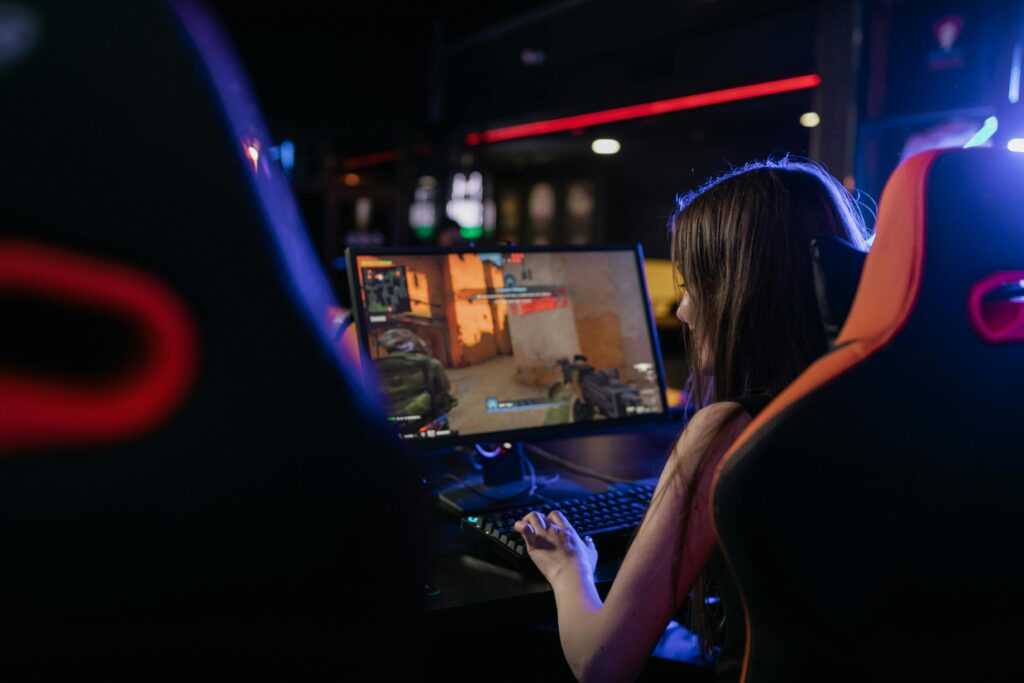 A woman is deeply engaged in playing computer games indoors, highlighting the gaming lifestyle.